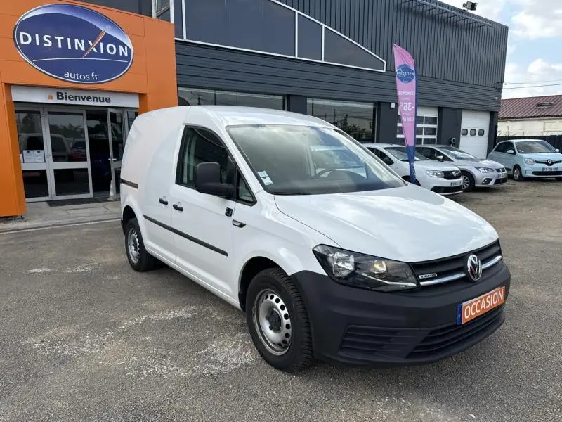 Volkswagen Caddy Van blanc Candy vu en 3/4 avant droit, avec calandre noire et plaque "OCCASION" orange.