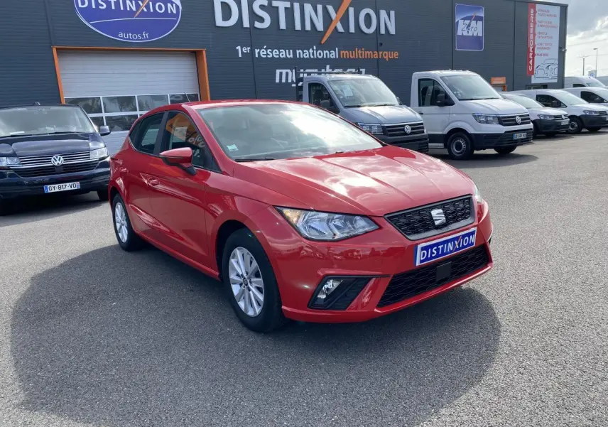 SEAT Ibiza rouge pur vue 3/4 avant droit sur parking avec calandre noire et jantes alliage 15 pouces.