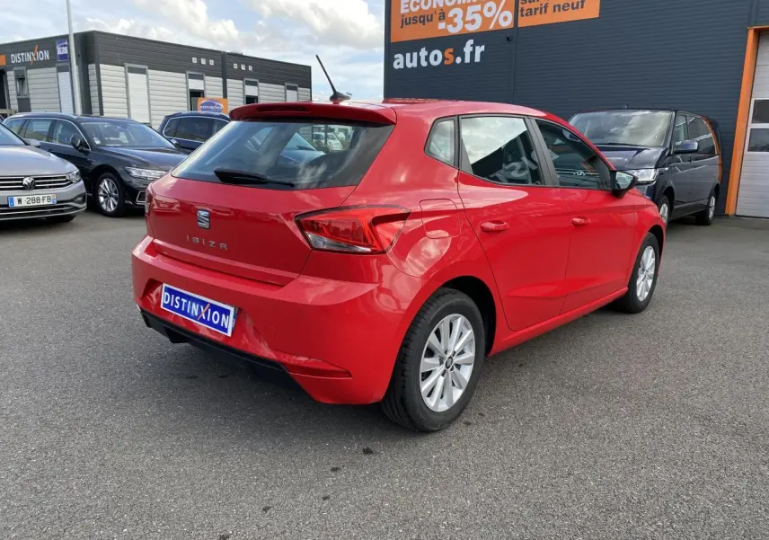 Vue 3/4 arrière droite d'une SEAT IBIZA rouge pur 2021 avec jantes alliage 15'' sur parking extérieur.