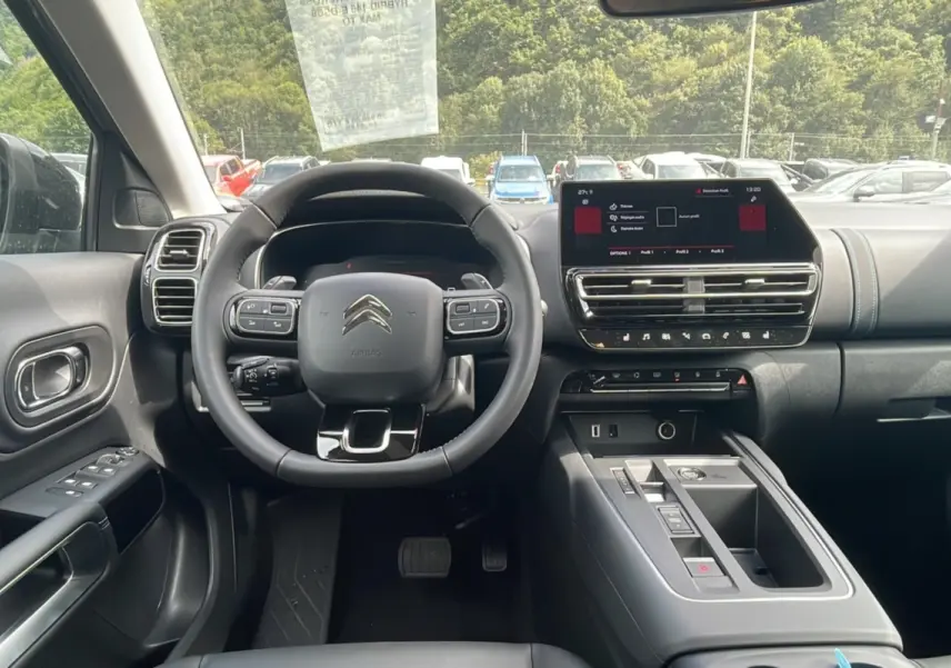 Intérieur moderne du Citroën C5 Aircross Hybrid 2025, vue frontale du tableau de bord avec écran tactile et volant multifonction.