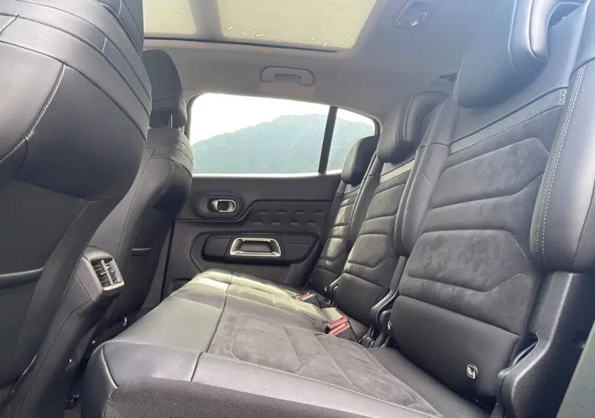 Vue latérale des sièges arrière en cuir noir du Citroën C5 Aircross Hybrid 2025, avec toit panoramique visible.