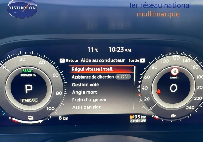 Tableau de bord digital du Nissan Qashqai blanc nacré, affichant l'aide au conducteur et la vitesse à 0 km/h.