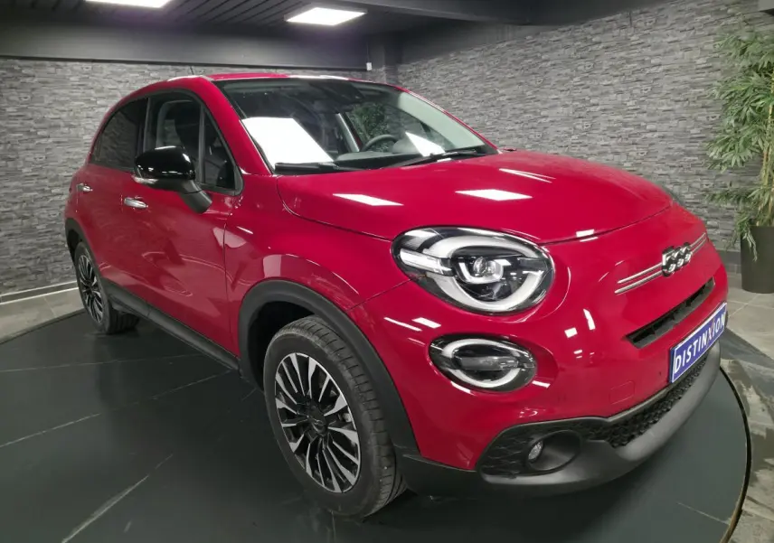 Fiat 500X rouge vue 3/4 avant droit, avec jantes alliage noires et coques de rétroviseurs noires.