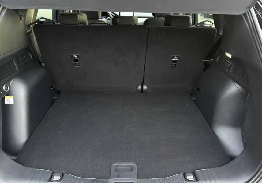 Coffre spacieux du Ford Kuga 2024 noir Obsidien, vue depuis l'arrière avec banquette arrière relevée et plancher plat.