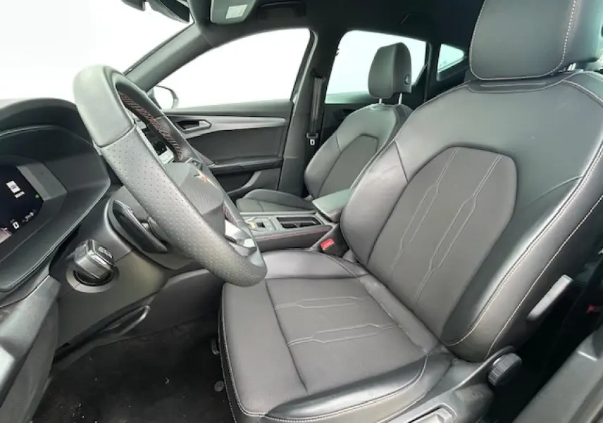 Vue intérieure côté conducteur du CUPRA Formentor 2025, sièges cuir noir avec surpiqûres contrastées et volant perforé.