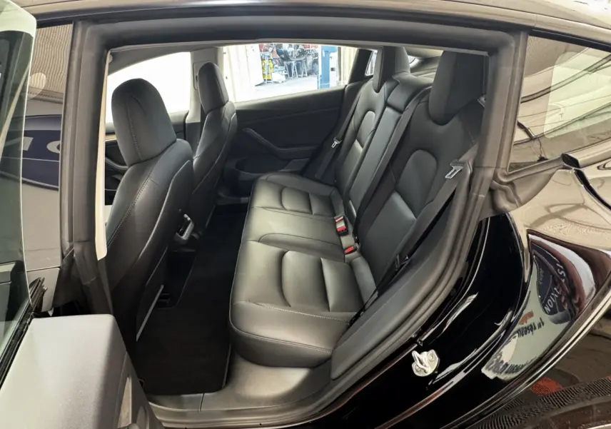 Vue intérieure côté droit montrant la banquette arrière en cuir noir d'une Tesla Model 3 Grande Autonomie 2023.