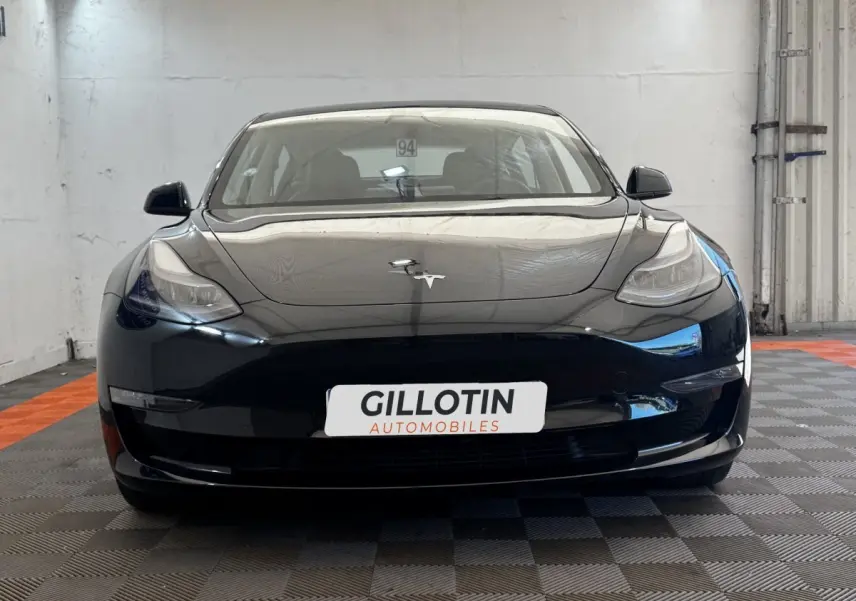 Vue frontale d'une Tesla Model 3 Grande Autonomie noire, avec logo Tesla visible sur le capot lisse.