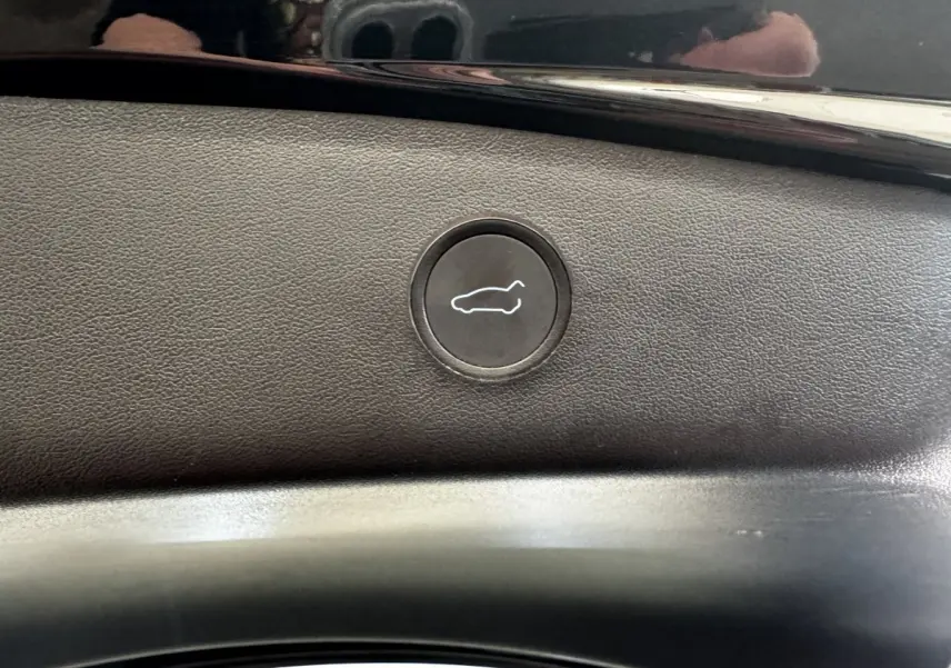 Bouton d'ouverture électrique du coffre sur panneau intérieur noir d'une Tesla Model 3 Grande Autonomie 2023.