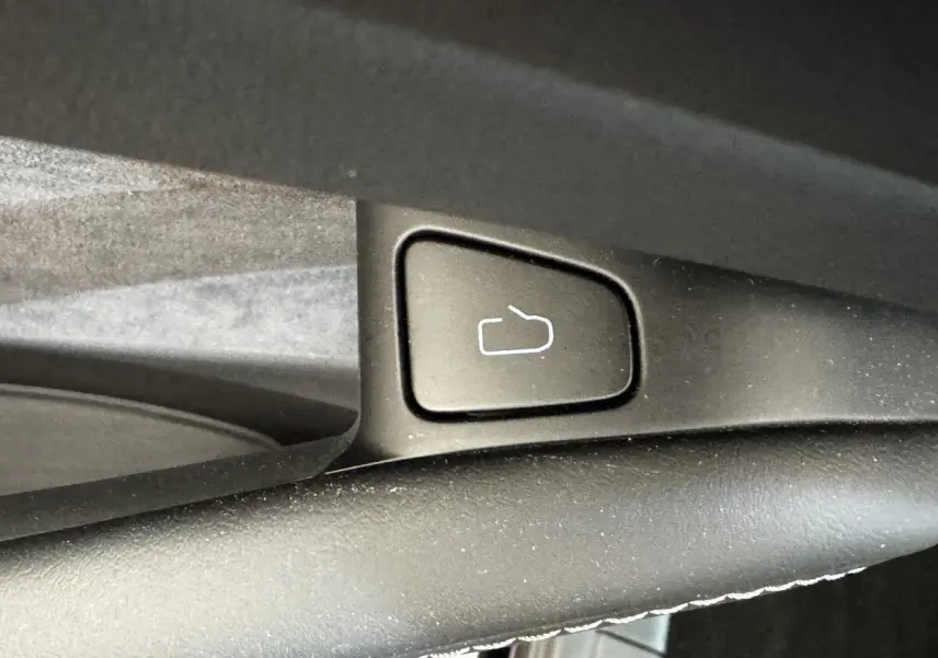 Bouton de déverrouillage de coffre noir sur la portière intérieure d'une Tesla Model 3 Grande Autonomie 2023.