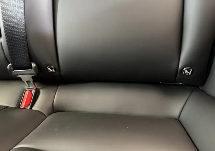 Gros plan sur la banquette arrière noire de la Tesla Model 3 2023 avec ceintures et fixations ISOFIX visibles.