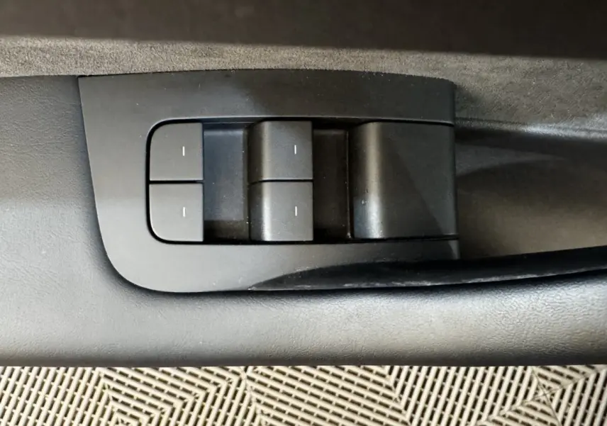 Détail des commandes de réglages mémorisables sur la portière intérieure d'une Tesla Model 3 noire 2023.