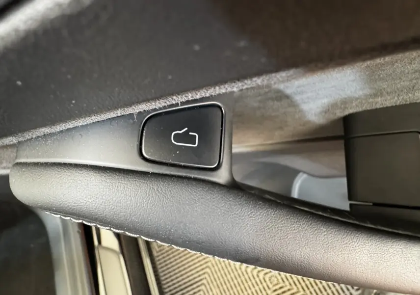 Détail du bouton de déverrouillage de porte sur la poignée intérieure noire d’une Tesla Model 3 Grande Autonomie 2023.
