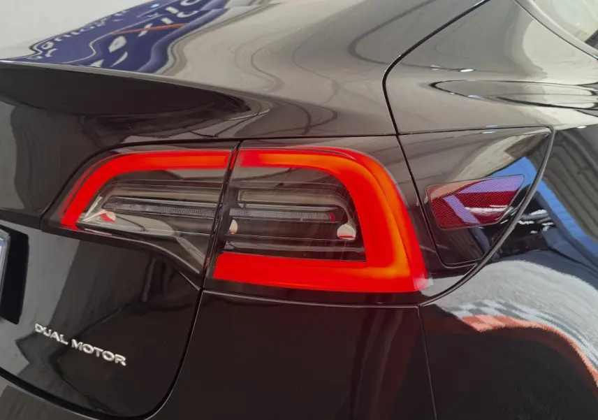 Gros plan sur le feu arrière droit rouge vif d’une Tesla Model 3 Grande Autonomie noire 2023, avec logo Dual Motor.