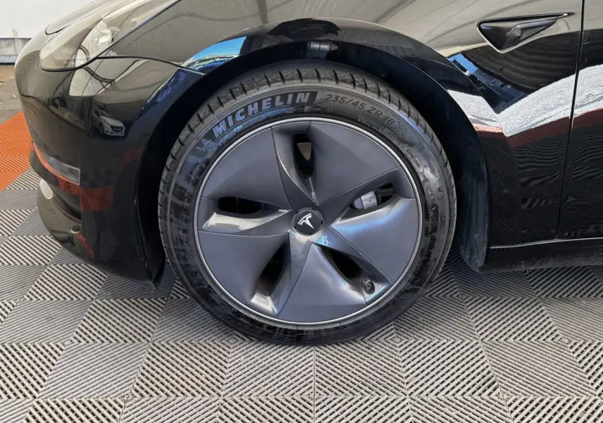 Gros plan sur la roue avant gauche noire d'une Tesla Model 3 2023 avec jante aérodynamique et pneu Michelin.