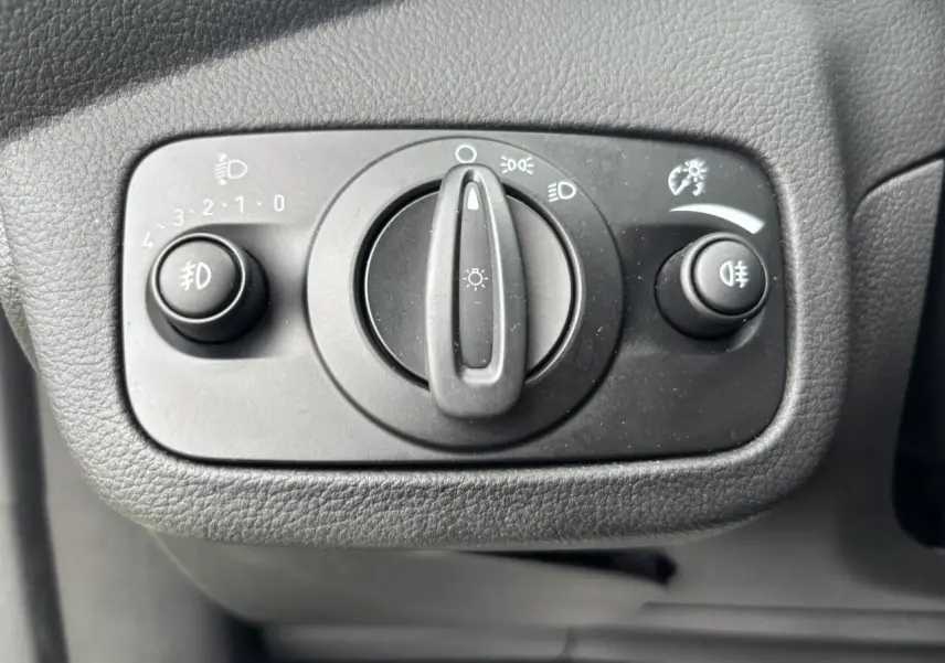 Gros plan sur le bouton de commande des phares et antibrouillards du tableau de bord d'une Ford C-MAX gris clair.