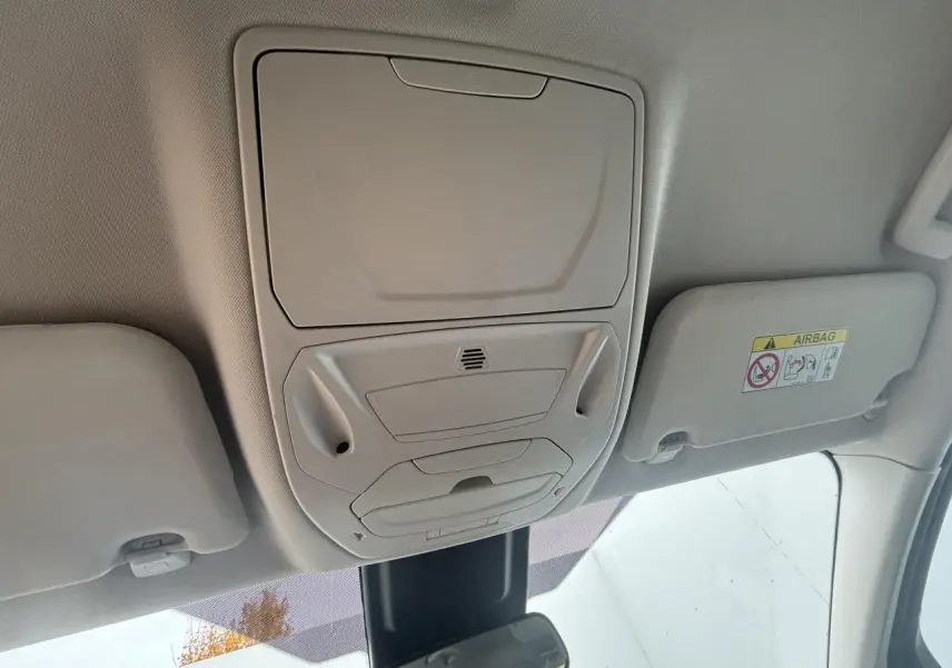 Vue intérieure du plafond avant d'une Ford C-MAX gris clair, montrant les commandes d'éclairage et les pare-soleil.