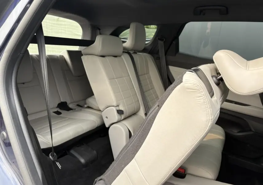 Vue intérieure arrière du Renault Espace VI 2023, sièges cuir gris sable clair avec toit panoramique visible.