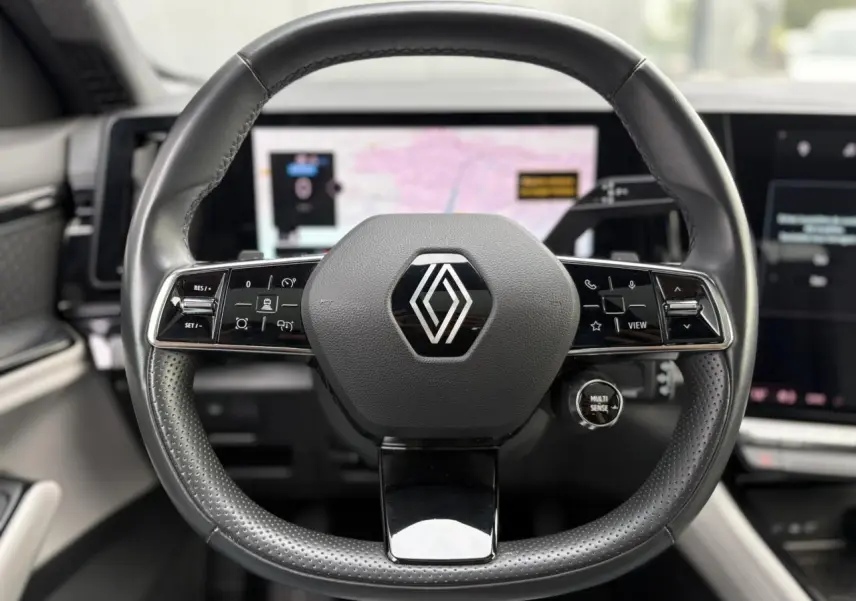 Volant cuir noir perforé de Renault Espace VI 6 E-Tech avec commandes intégrées et logo central, vue frontale intérieure.