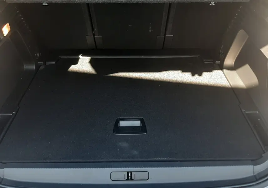 Coffre ouvert vu de l'arrière du Citroën C5 Aircross gris Artense avec toit noir, montrant le plancher plat et l'espace de rangement.