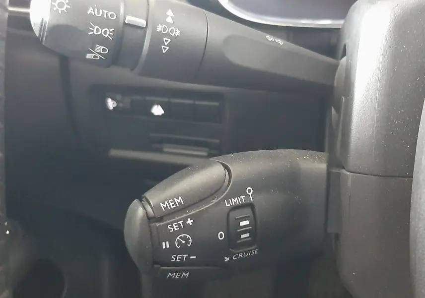 Gros plan sur les commandes de régulateur et feux au volant d’un Citroën C5 Aircross 1.2 PureTech 130ch Feel, intérieur noir.