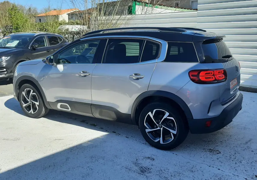 Vue 3/4 arrière droite d'un Citroën C5 Aircross gris Artense avec toit noir et feux arrière LED distinctifs.