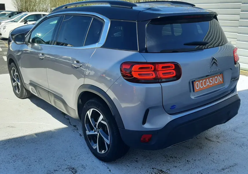 Vue 3/4 arrière droite d'un Citroën C5 Aircross gris Artense avec toit noir et feux arrière LED distinctifs.