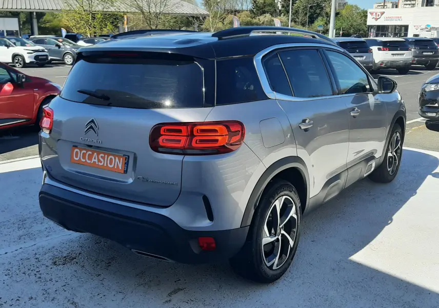 Vue 3/4 arrière droite du Citroën C5 Aircross gris Artense avec toit noir, feux arrière LED et jantes bicolores.