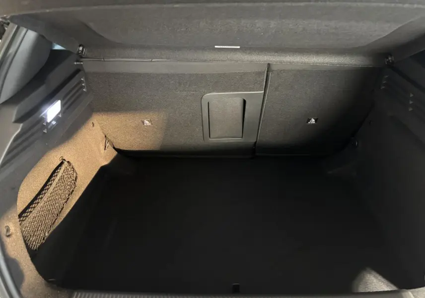 Coffre ouvert de la Peugeot 308 hybride blanche, vue intérieure montrant un espace de rangement propre et bien éclairé.