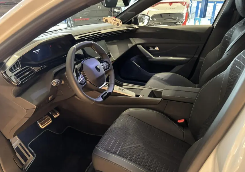 Intérieur avant droit de Peugeot 308 blanc Okenite 2026, volant compact GT cuir et tableau de bord numérique.