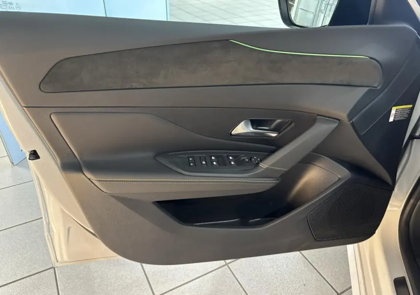 Vue côté gauche de la porte avant noire avec surpiqûres vert Adamite et insert Alcantara du Peugeot 308 Hybrid 2026 blanc Okenite.