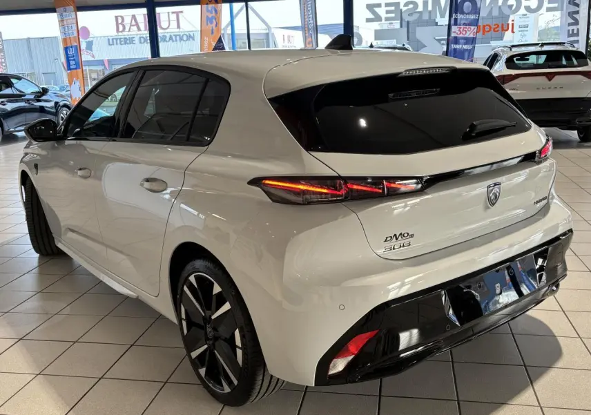 Vue 3/4 arrière droit d'une Peugeot 308 blanche Okenite avec feux arrière LED 3 griffes et jantes alliage bi-tons.