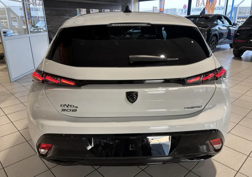 Vue arrière d'une Peugeot 308 Hybrid blanche Okenite avec feux arrière LED en forme de griffes et logo lion central.