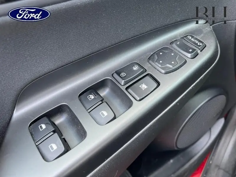 Gros plan sur la commande des vitres électriques côté conducteur d'une Hyundai Kona rouge, avec haut-parleur intégré.