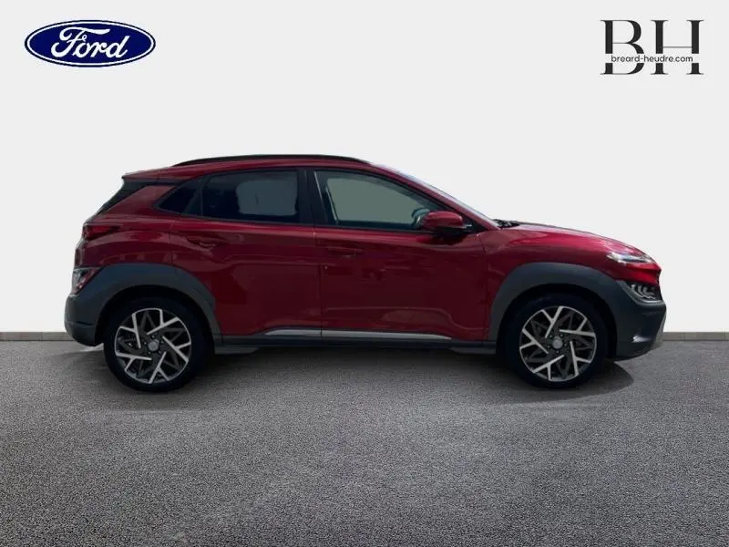 Vue de profil côté gauche d'un Hyundai Kona rouge Pulse Métal avec jantes alliage et protections noires.
