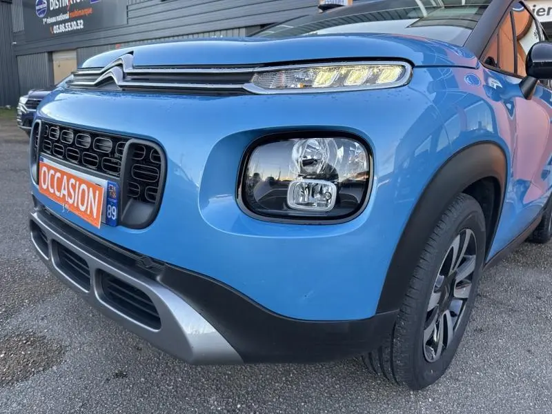Vue 3/4 avant droit d'une Citroën C3 Aircross Bleeding Blue avec phares carrés et calandre noire distinctive.