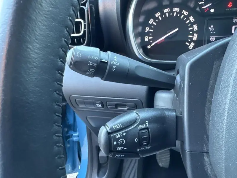 Gros plan sur les commandes au volant du Citroën C3 Aircross Bleu Breathing, avec tableau de bord et compteur visibles.