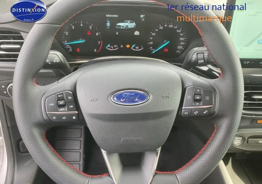Volant perforé avec coutures rouges et tableau de bord numérique de la Ford Focus gris 2025 vue de face intérieure.