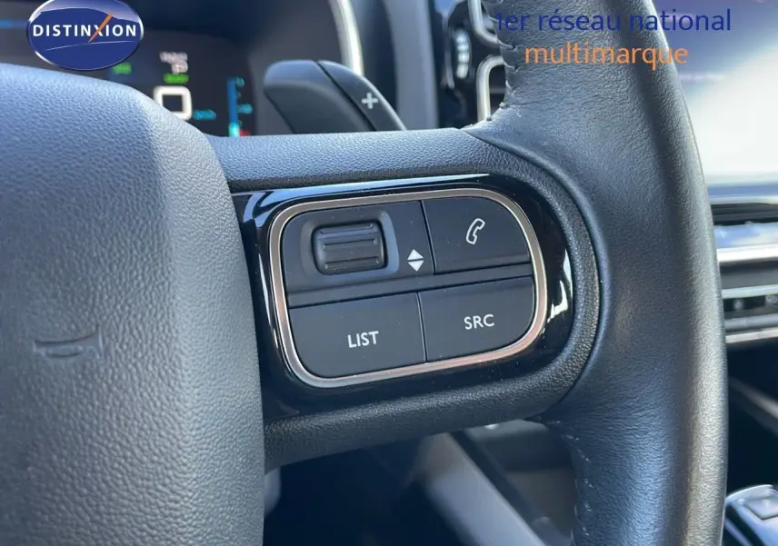 Gros plan sur les commandes gauche du volant cuir noir du Citroën C5 Aircross blanc nacré 2021 hybride.