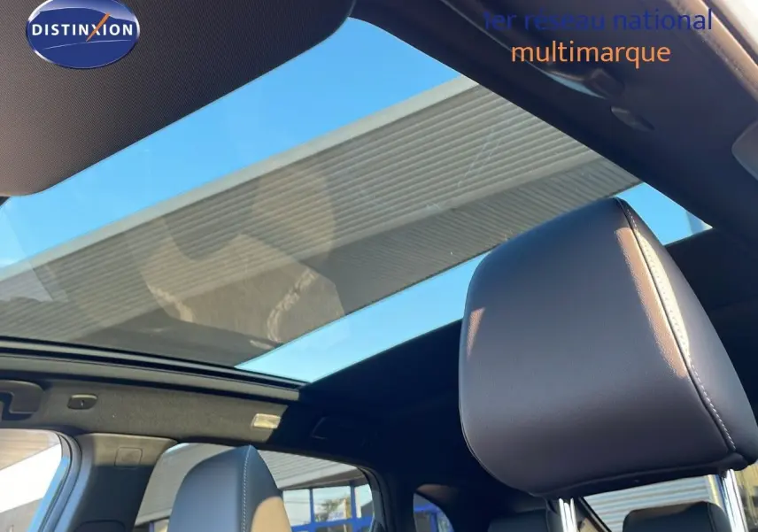 Vue intérieure du Nissan Qashqai 2025 avec toit panoramique et sièges en cuir noir visibles côté droit.