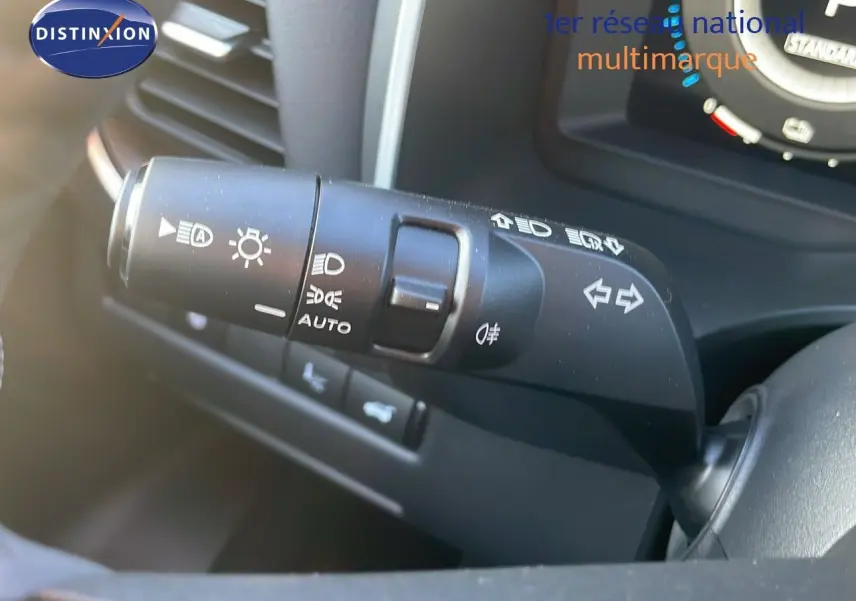 Gros plan sur la commande des phares et clignotants du Nissan Qashqai 2025, intérieur noir avec tableau de bord partiel visible.