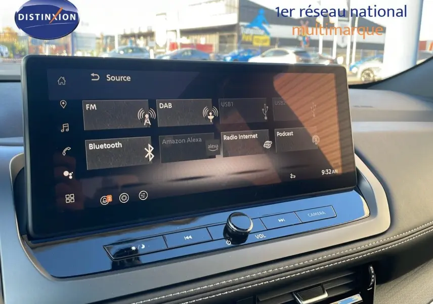 Écran tactile central du Nissan Qashqai 2025 affichant les sources audio avec tableau de bord gris et coutures blanches visibles