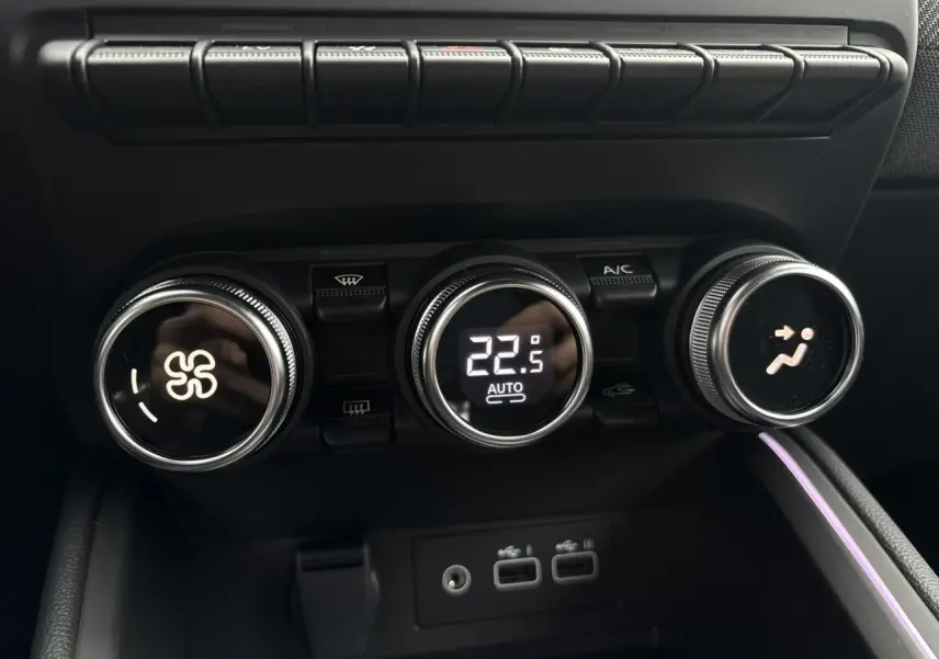 Gros plan sur les commandes de climatisation digitale et les ports USB dans l'habitacle noir de la Renault Clio 2025.