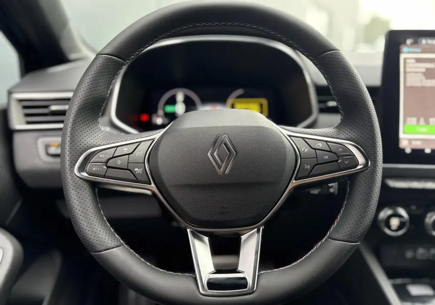 Volant multifonction en cuir noir avec logo Renault, tableau de bord numérique et écran tactile à droite.