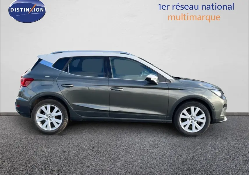 Vue de profil côté gauche d’un SEAT Arona gris falaise métallisé avec toit blanc, roues alliage et cinq portes visibles.