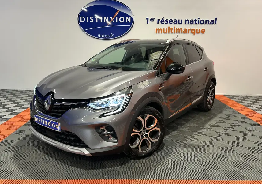 Renault Captur gris en 3/4 avant droit, avec phares LED allumés et jantes alliage distinctives.
