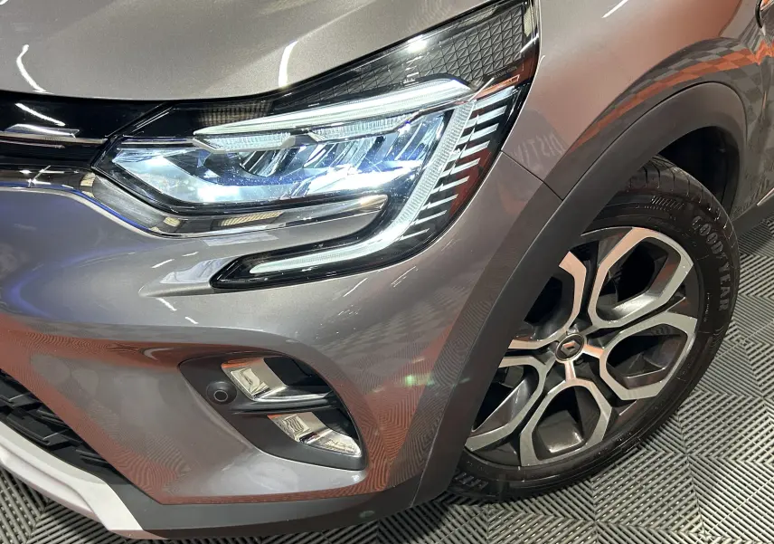 Gros plan sur l'avant droit gris du Renault Captur 2020, mettant en valeur le phare LED et la jante alliage distinctive.