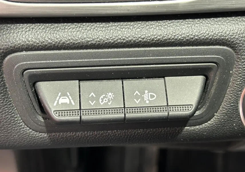 Gros plan sur les boutons de réglage d'assistance à la conduite et des phares dans un Renault Captur gris de 2020.
