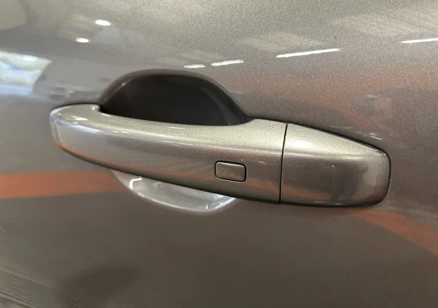 Poignée de porte gris métallisé du côté gauche d'un Renault Captur 2020, finition soignée avec bouton intégré.