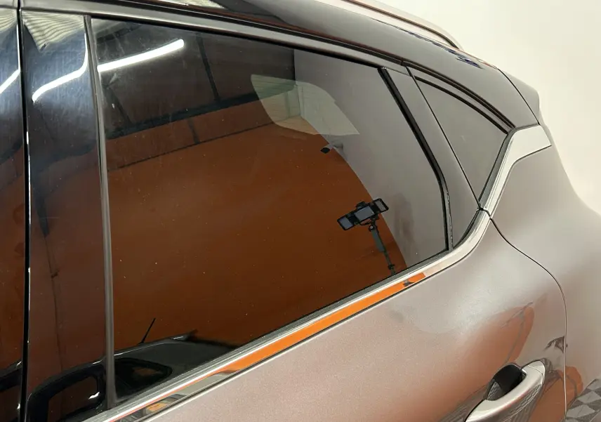 Détail du côté droit arrière gris métallisé du Renault Captur 2020 avec vitre teintée et poignée de porte intégrée.