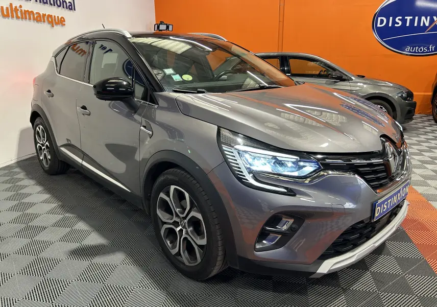Renault Captur gris 3/4 avant droit avec phares LED allumés, jantes alliage et calandre noire brillante.